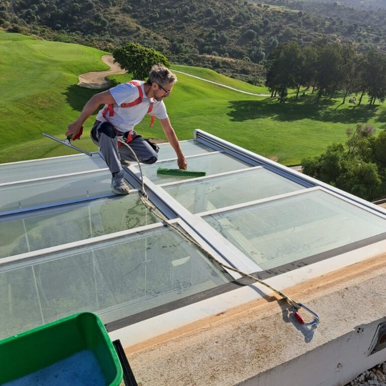 Profesional de Sergio Facility Service realizando limpieza de cristales en altura con medidas de seguridad en Marbella.