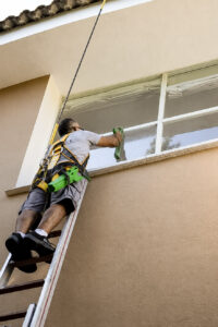 Limpieza profesional de cristales en altura con equipo de seguridad y herramientas especializadas – Sergio Facility Service.