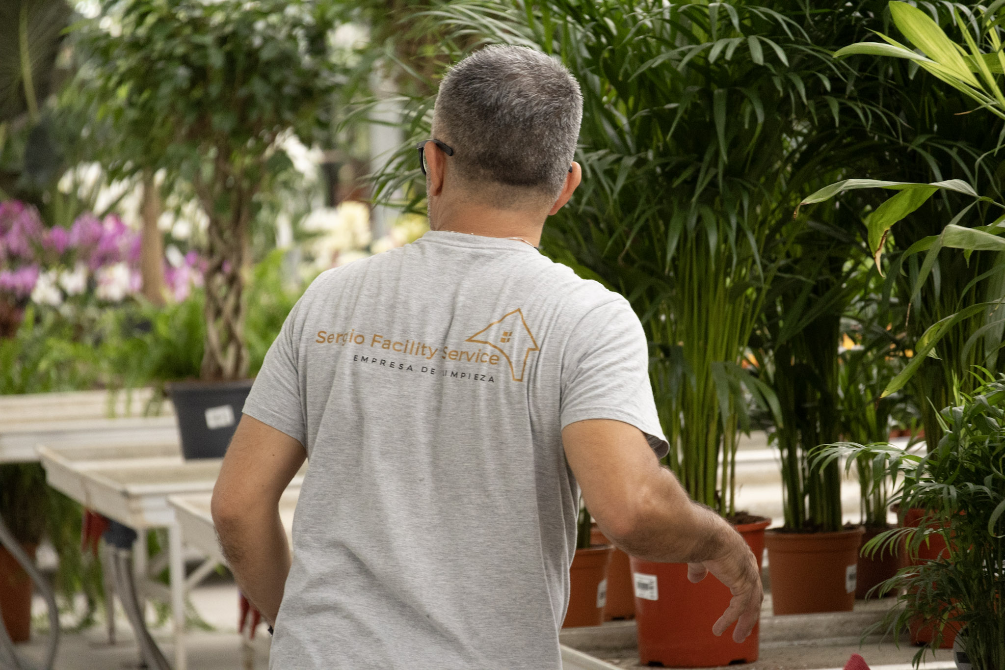 Profesional de Sergio Facility Service realizando trabajos de mantenimiento en una zona comercial con plantas y vegetación en Marbella.
